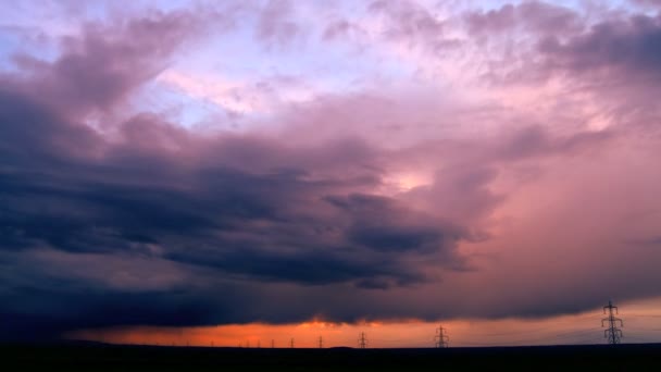 Nubes de tormenta de lapso de tiempo al atardecer sobre un horizonte lleno de torres eléctricas — Vídeo de stock