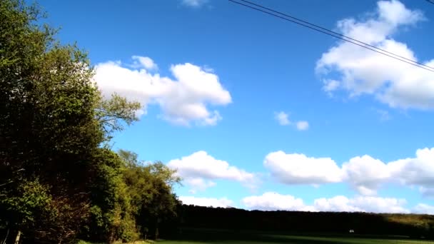 Eletricidade pilão em um campo com céu azul e nuvens brancas — Vídeo de Stock