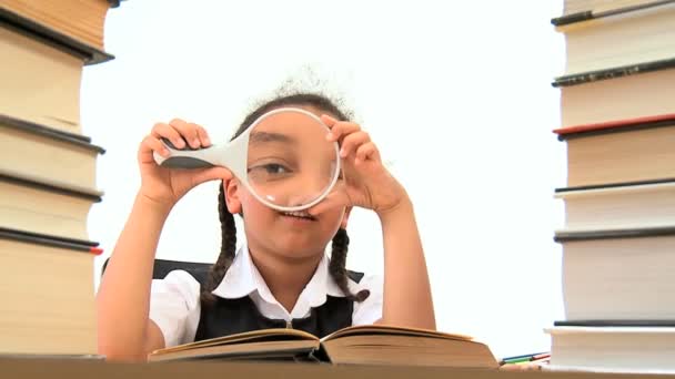 Cute african american schoolgirl using a spy glass with a book — Stock Video