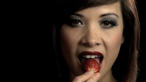 Sensuous western oriental girl slowly biting into a strawberry — Stock Video