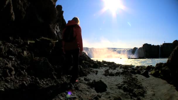 Одинокая молодая женщина достигает потрясающего водопада в своем походе приключения — стоковое видео