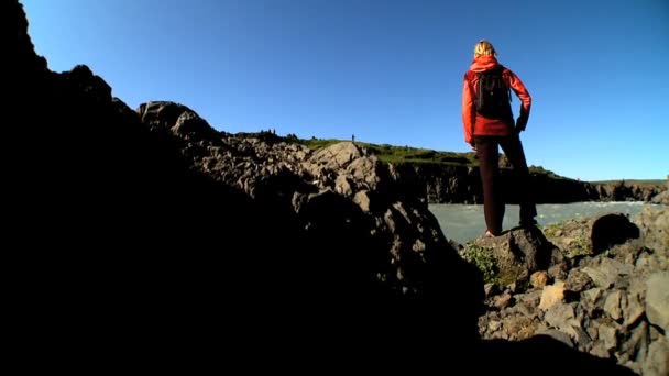 Одинокая женщина рядом с быстротекущей водой на ее туристических приключений — стоковое видео