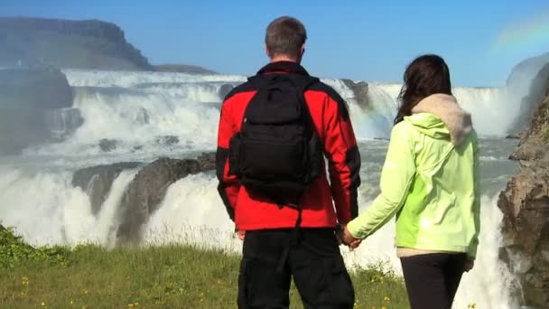 Atlético joven eco-turistas senderismo frente a la cascada glacial — Vídeo de stock