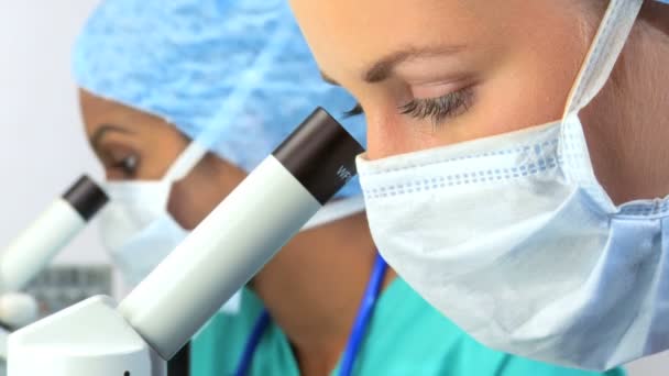 Close-up van medische onderzoekers met masker op met een Microscoop — Stockvideo