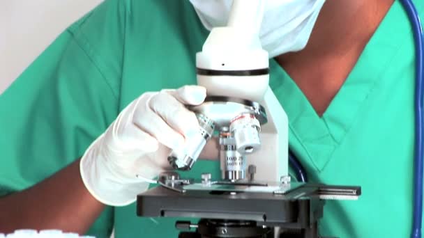 Médecin féminin regardant à travers un microscope — Video