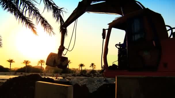 Mechanischer Bagger in Silhouette, der bei Sonnenuntergang auf der Baustelle arbeitet — Stockvideo