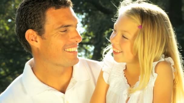 Young father tenderly holding his daughter while outdoors on a summers day — Wideo stockowe