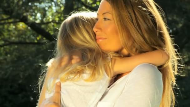 Привлекательная мать нежно держит дочь на улице в летний день. — стоковое видео