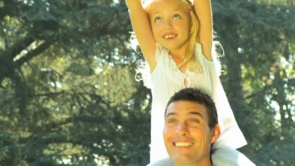 Giovane padre che tiene la figlia sulle spalle mentre è all'aperto in un giorno d'estate — Video Stock