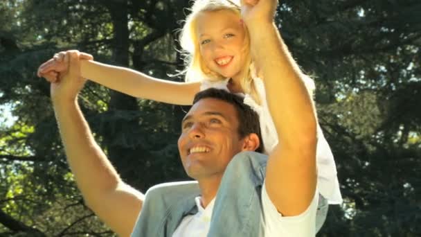 Μικρά πατέρας γέλιο με την κόρη του στους ώμους του, ενώ σε εξωτερικούς χώρους σε την ημέρα καλοκαίρια — Αρχείο Βίντεο