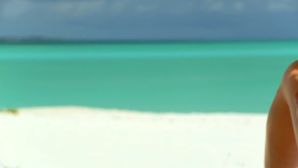 Elegantní mladá žena uvolňující na bílé písečné pláži při pohledu na akvamarín vody — Stock video