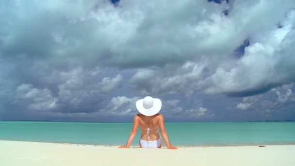 Serena joven mujer tomando el sol y soñando bajo nubes tropicales — Vídeos de Stock