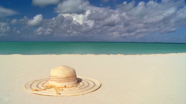 Chapeau de soleil élégant en paille sur plage de sable blanc et mer bleue aqua — Video