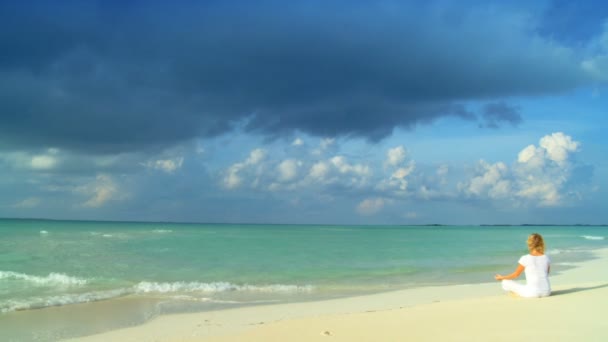 Mujer joven y serena relajándose con yoga en una hermosa playa tropical — Vídeos de Stock