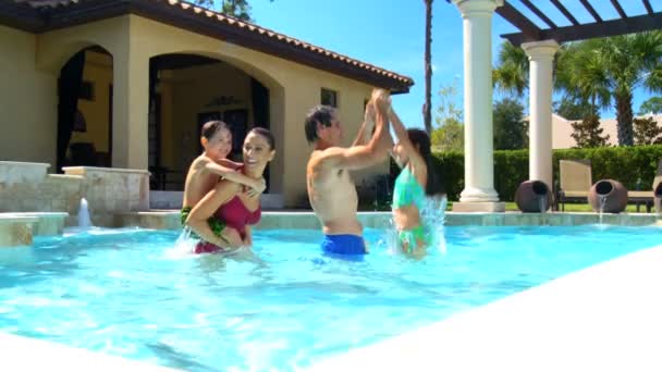 Attractive young caucasian family enjoying leisure time together in their luxury swimming pool — Stock Video