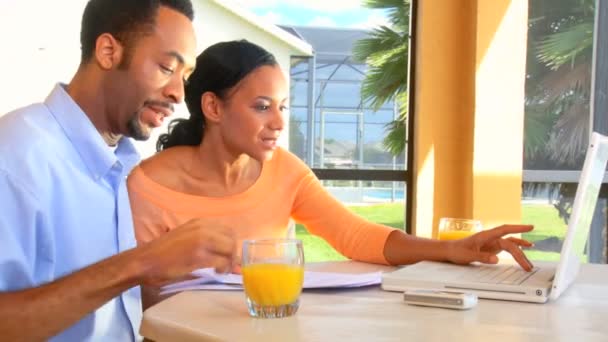 Aantrekkelijke jonge Afrikaanse Amerikaanse echtpaar met behulp van een laptop te maken plannen voor de toekomst — Stockvideo