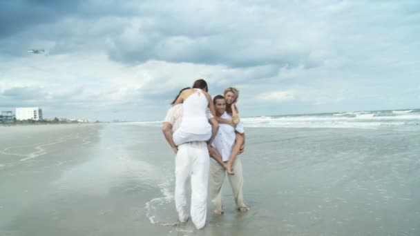 Quatre jeunes amis adultes attrayants s'amusent sur la plage ensemble — Video