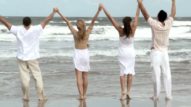 Cuatro atractivos amigos adultos jóvenes que se divierten juntos en la playa — Vídeo de stock