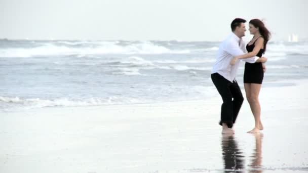 Двоє молодих закоханих розважаються на пляжі рано вранці після соціальної ночі — стокове відео