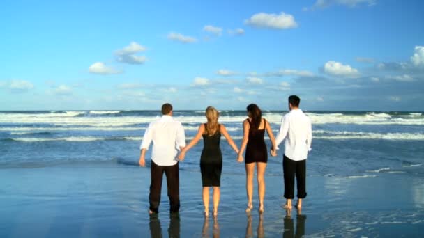 Quatre jeunes amis attrayants qui s'amusent sur la plage tôt le matin après une soirée sociale — Video