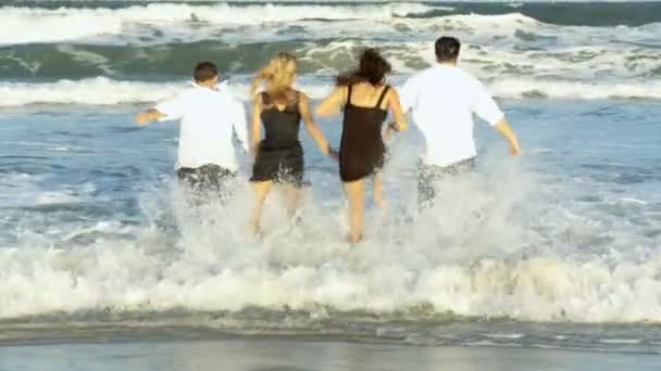 Quatre jeunes amis attrayants qui s'amusent fou dans l'océan tôt le matin après une soirée sociale — Video