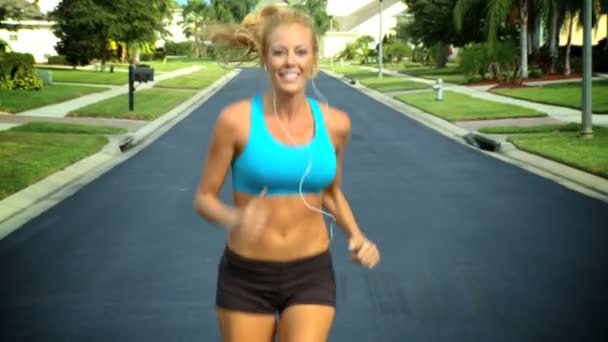 Vacker blond kvinna njuter av jogging längs förorts vägar i solskenet — Stockvideo