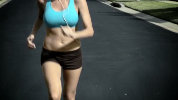 Slim jeune femme jogging le long des routes de banlieue au soleil — Video