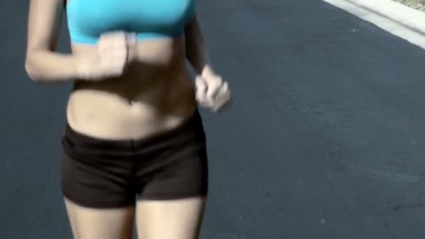 Schlanke junge Frau joggt bei Sonnenschein über Vorstadtstraßen — Stockvideo