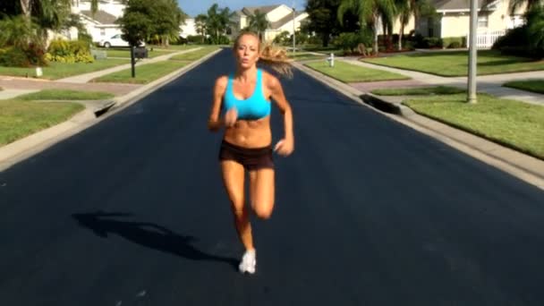 Bella bionda femmina godendo di jogging lungo le strade suburbane sotto il sole — Video Stock