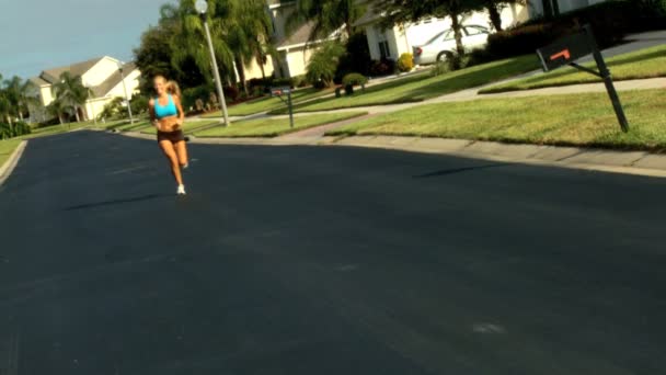 Belle femme blonde profitant du jogging le long des routes de banlieue au soleil — Video