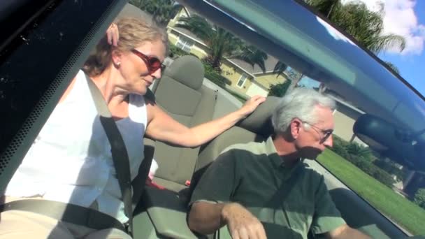 Pareja jubilada contenta disfrutando de conducir a casa bajo el sol en su coche de techo abierto — Vídeo de stock