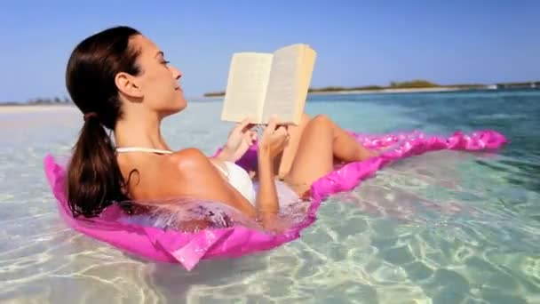 Yatakta kitap ile yüzen üzerinde güzel bir kadın — Stok video