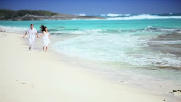 Pareja caucásica corriendo a lo largo de la playa tropical — Vídeos de Stock