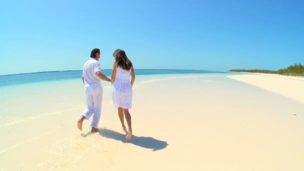 Pareja corriendo en las aguas poco profundas a lo largo de la playa tropical — Vídeo de stock