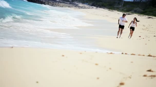 Gesundes junges Paar joggt am Strand entlang — Stockvideo