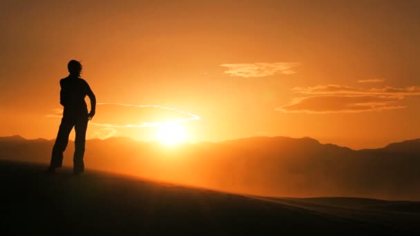 Hembra solitaria en silueta caminando a través de dunas de arena y viendo la puesta de sol — Vídeo de stock