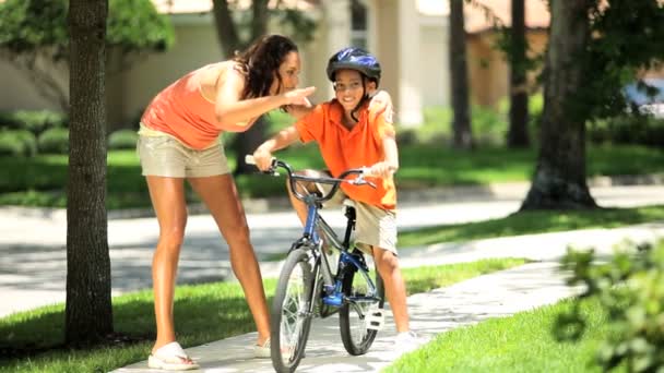 Joven madre étnica alentando a su hijo en bicicleta — Vídeo de stock