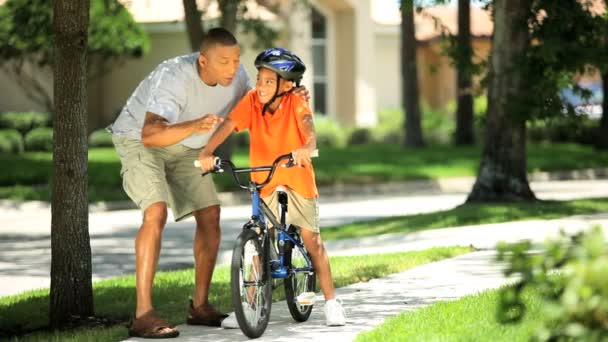 Joven padre étnico alentando a su hijo en bicicleta — Vídeo de stock