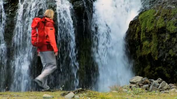 Női természetjáró elérése egy jeges vízesés — Stock videók
