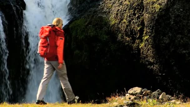 Jonge vrouw op expeditie wandelen door waterfall — Stockvideo