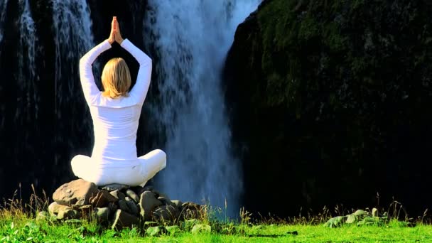 Kvinna i vitt som utför yoga av vattenfall — Stockvideo
