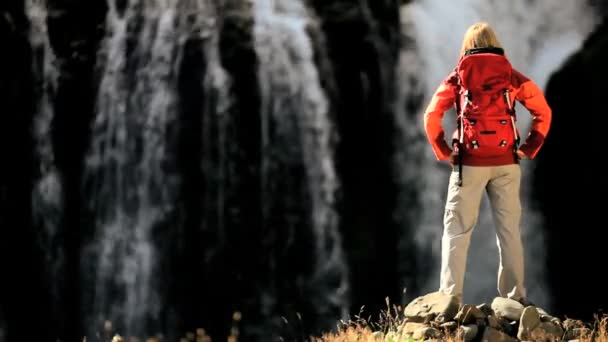 Vrouwelijke wandelaar rusten op een waterval — Stockvideo