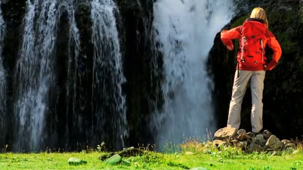 Vrouwelijke wandelaar bereiken een glaciale waterval — Stockvideo