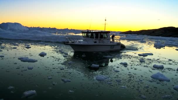 Nautische vaartuig bij zonsondergang in ice floes met ijsbergen — Stockvideo