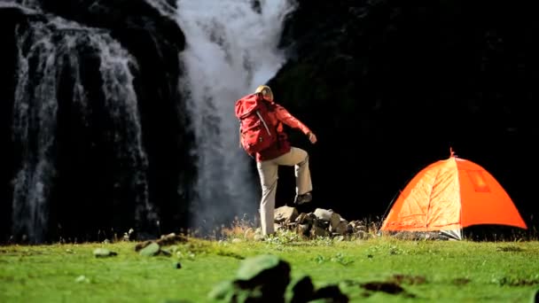 Ensamstående kvinnliga vandrare av tältet på vattenfall — Stockvideo