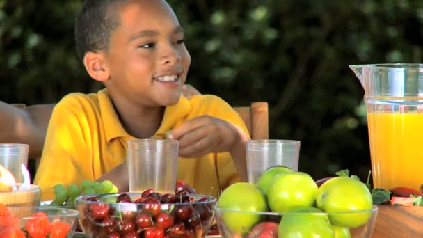 Petit garçon ethnique dégustant du raisin avec déjeuner — Video