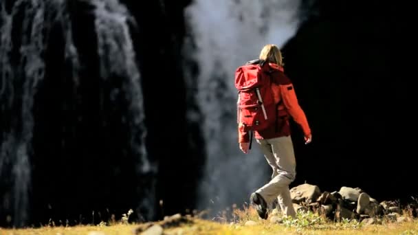 Молодой турист смотрит на каскадный водопад — стоковое видео