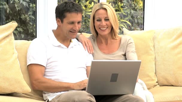 Atractiva pareja caucásica usando el ordenador portátil en casa — Vídeo de stock