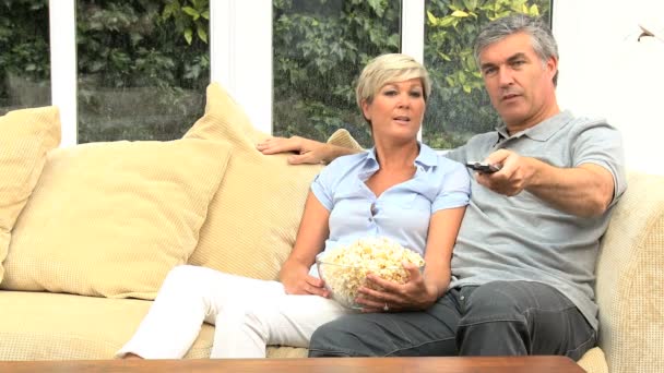 Attraente coppia matura guardando la TV con popcorn — Video Stock