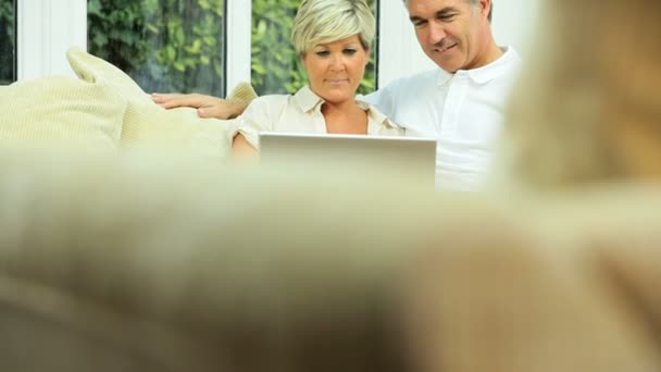 Mellersta äldre par med laptop hemma — Stockvideo